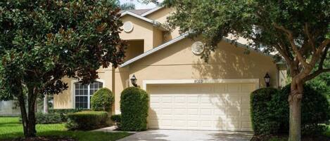 A residential house with a beige exterior, a white garage door, and a well-maintained lawn.