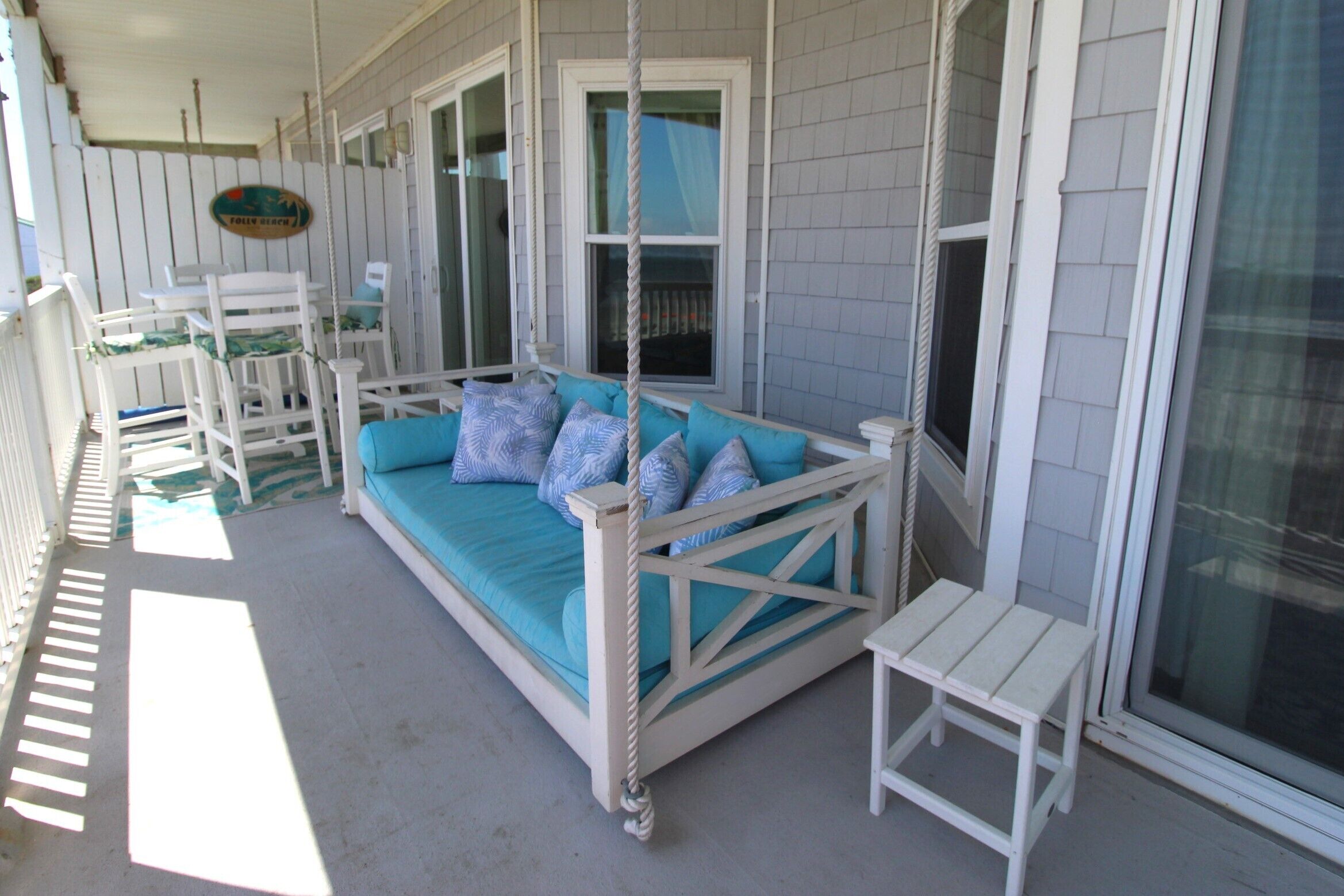 A porch with a swing seat, a small table, and a chair.