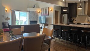 Cozinha moderna com ilha central, banquetas e área de refeições com mesa e cadeiras.