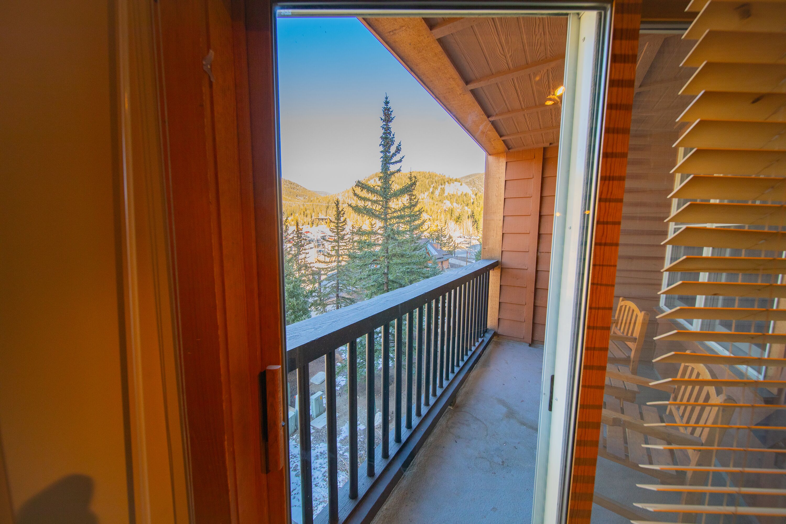 A balcony with a wooden railing overlooking a snowy mountain landscape.