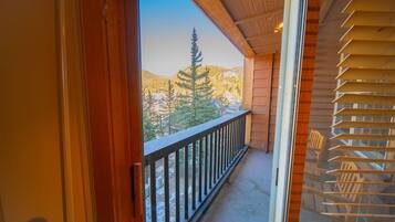 A balcony with a wooden railing overlooking a snowy mountain landscape.