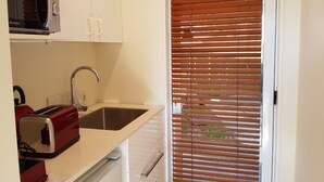 A kitchen with a toaster, sink, and cabinets. - Annandale Accommodation (Taupo)
