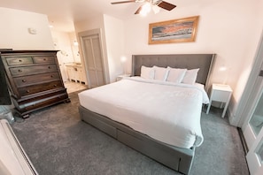 A bedroom with a large bed, a dresser, a nightstand, and a ceiling fan. - Springs 8857 (Keystone)