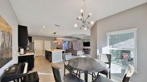 A modern kitchen with a dining area, featuring a round table, chairs, and a piano. - 3 bedroom ranch near Jax airport this charming home is set up for play or work. (Jacksonville)