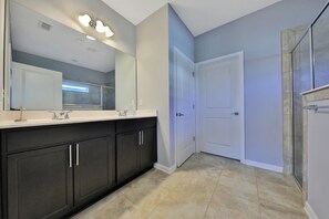 Un baño moderno con un espejo grande, muebles oscuros y una puerta blanca.