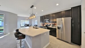 A modern kitchen with a large island, stainless steel appliances, and a pendant light fixture. - 3 bedroom ranch near Jax airport this charming home is set up for play or work. (Jacksonville)