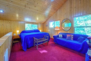 A wooden cabin room with two beds, a sofa, a mirror, and a window. - North Carolina Escape w/ Deck, Grill & Fire Pit! (Bryson City)