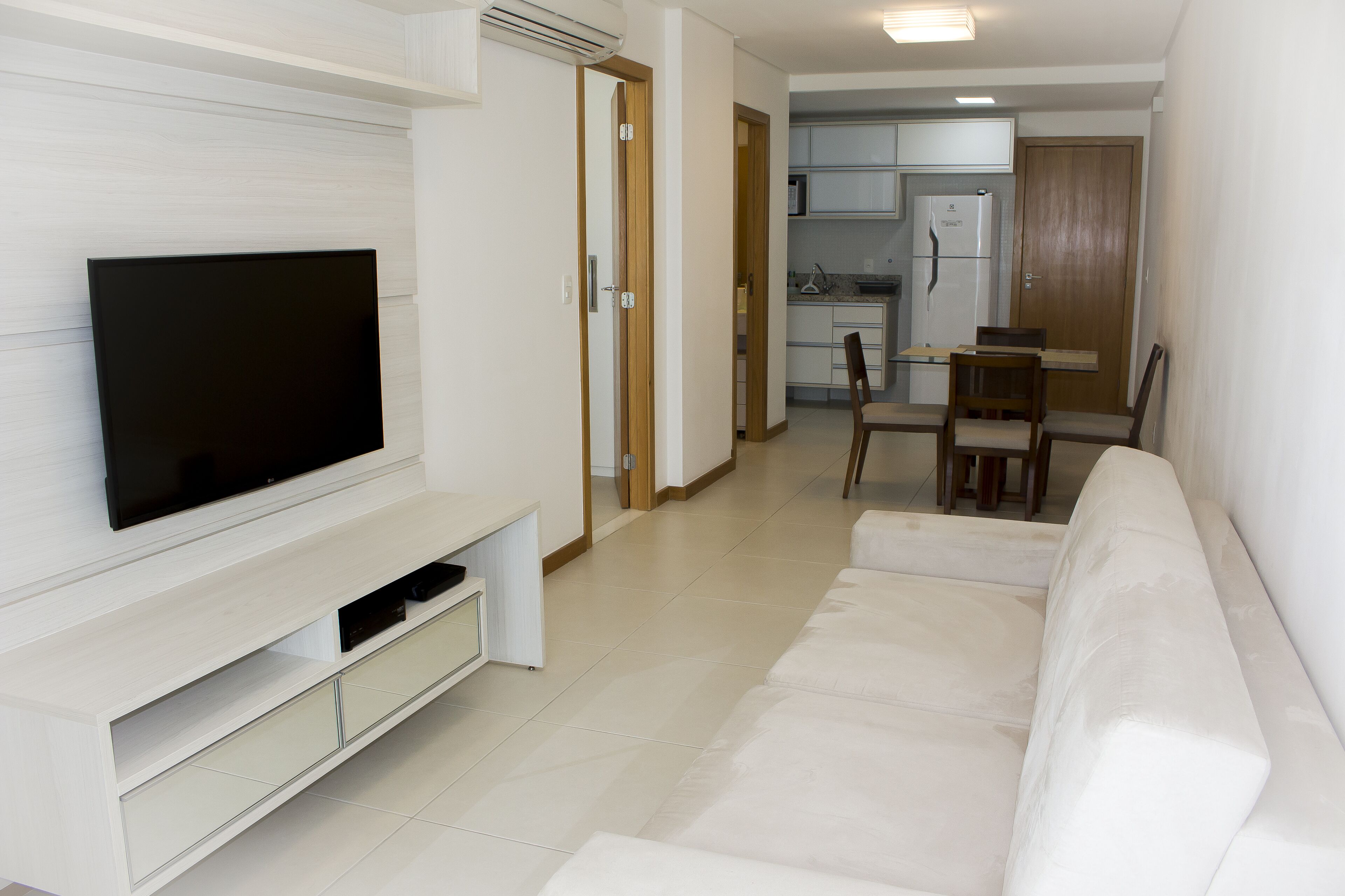 Un soggiorno moderno con una TV a schermo piatto, un divano e un'area pranzo con tavolo e sedie.