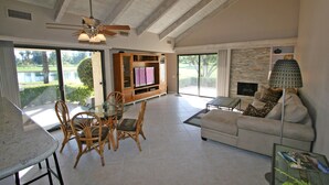 Un vaste salon doté d’une porte vitrée donnant sur un patio, d’une cheminée et d’un ventilateur de plafond.