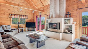 Ein gemütliches Blockhaus-Interieur mit Kamin, Ledersofas und einem Fernseher.