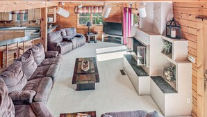 Ein gemütliches Blockhaus-Interieur mit Wohnbereich, Sofa, Couchtisch, Fernseher und Küche.