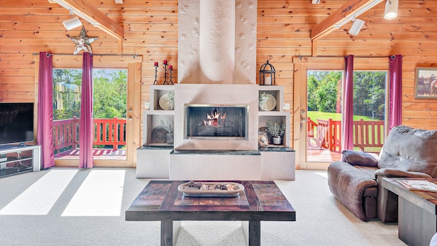 Ein gemütliches Wohnzimmer mit Kamin, Holzwänden und einer bequemen Sitzecke.