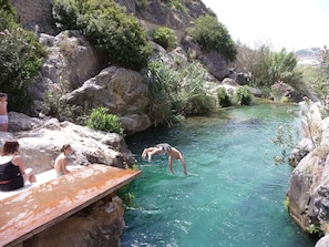 A natural pool with clear water surrounded by rocks and greenery.