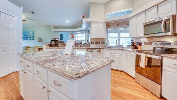 A spacious kitchen with white cabinetry, granite countertops, stainless steel appliances, and a large island.