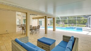 An outdoor patio area with wicker furniture and a pool.