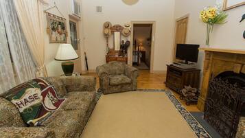 A living room with a sofa, armchair, fireplace, television, and decorative items.