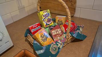 Una cesta de mimbre llena de varias cajas de cereales Kellogg's sobre una encimera de cocina.