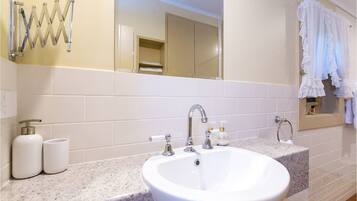 A bathroom with a white sink, two faucets, a mirror, and a towel rack.