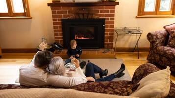 Una sala de estar acogedora con chimenea, un sofá y un niño jugando.