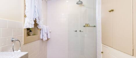 A bathroom with a shower, a sink, and a vanity with a mirror.