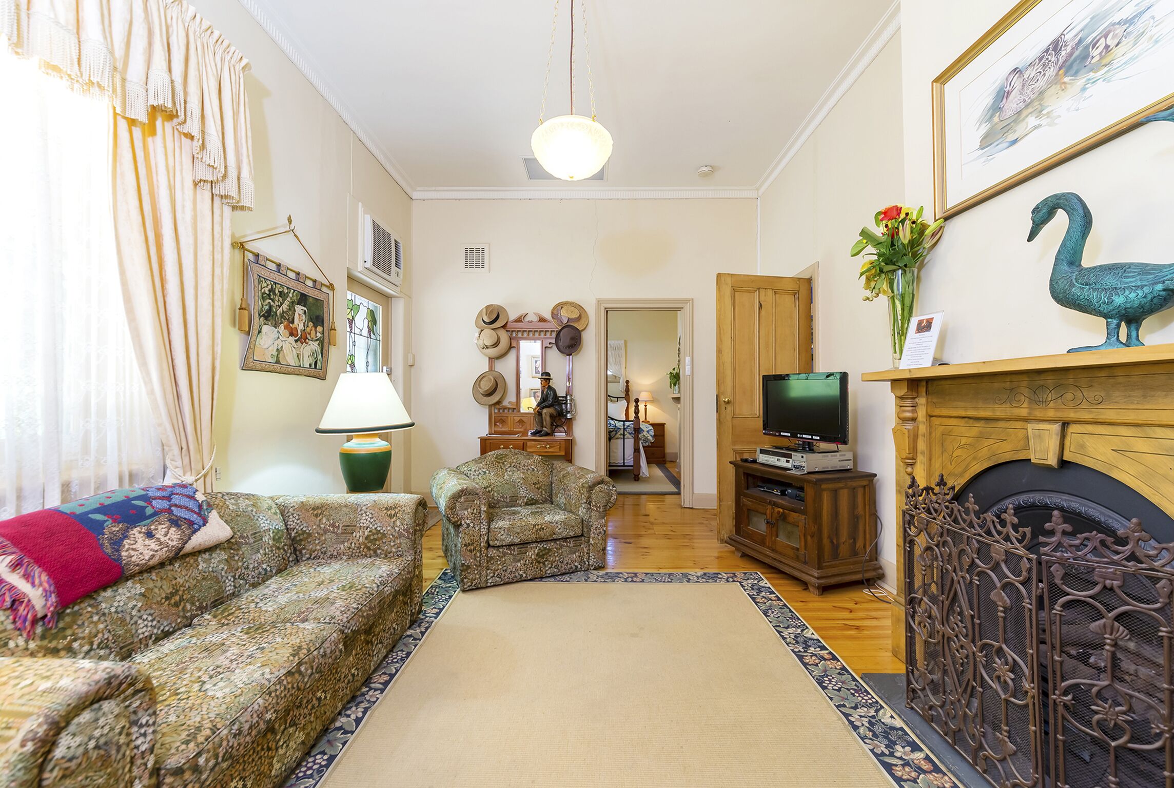 Una sala de estar con sofá, sillón, chimenea, televisor y objetos decorativos.