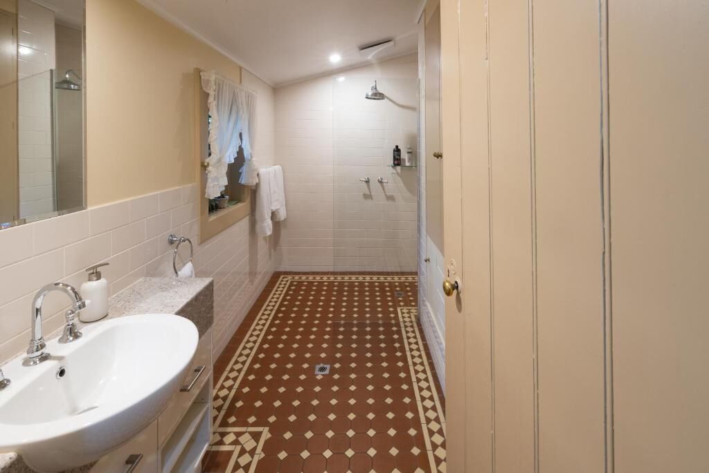 Un baño con lavamanos blanco, ducha y piso estampado.