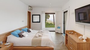 A hotel room with a large bed, a TV, a wooden dresser, and a view of the outdoors. - Holiday rental villa with swimming pool in Begur, Casa de camp (Begur)