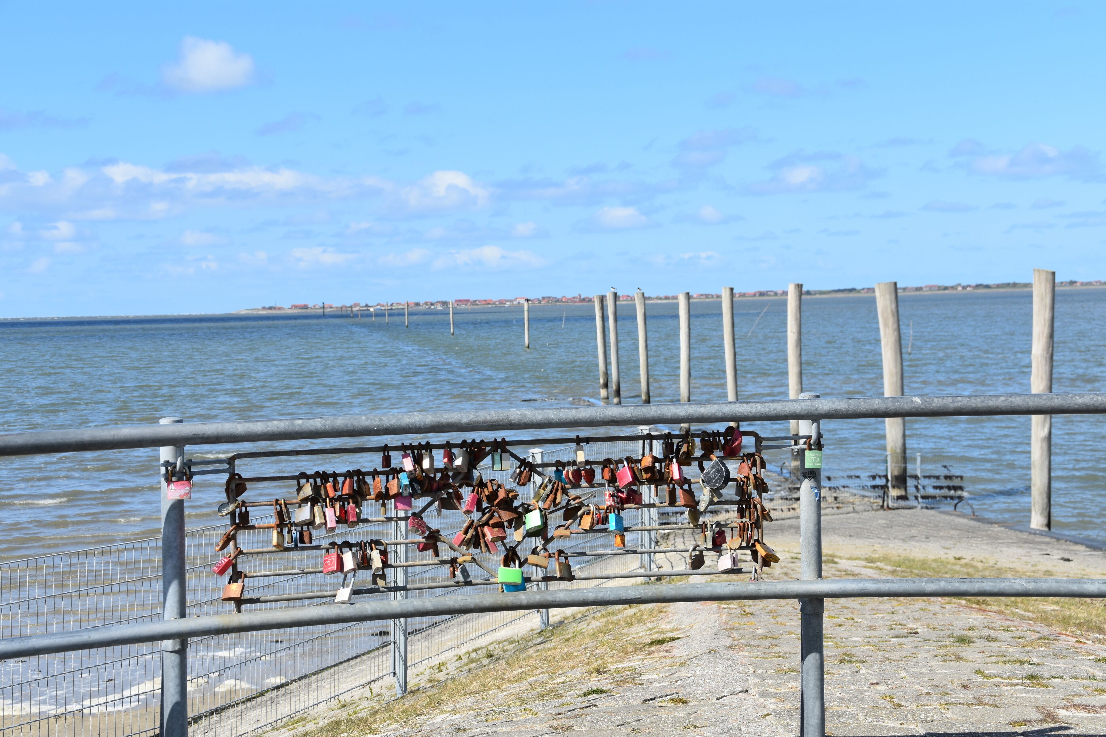 A waterfront promenade with a metal railing and a series of locks attached to it.
