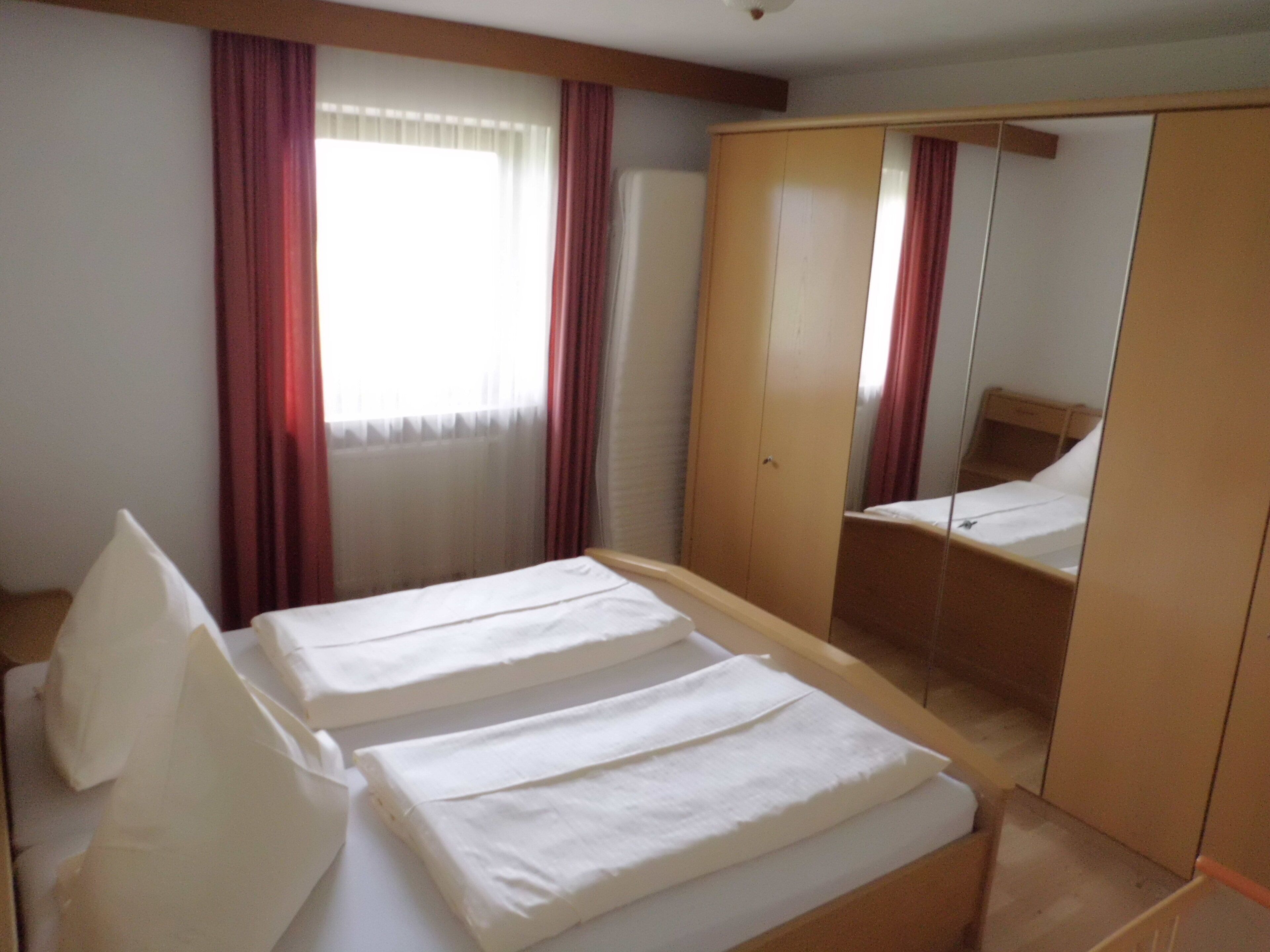 Une chambre d’hôtel avec deux lits, une armoire et une fenêtre avec des rideaux.