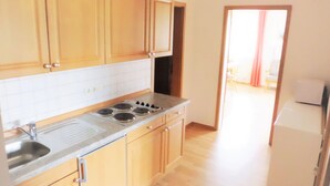 A kitchen with wooden cabinets, a stainless steel sink, and a stove. - Vacation apartment B, 4 persons with balcony or terrace, bedroom, 50 to 55 sqm (Inzell)