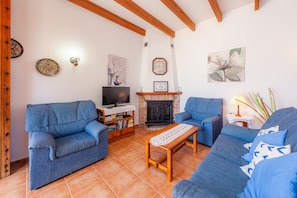 A living room with blue sofas, a wooden coffee table, a fireplace, and wall art.