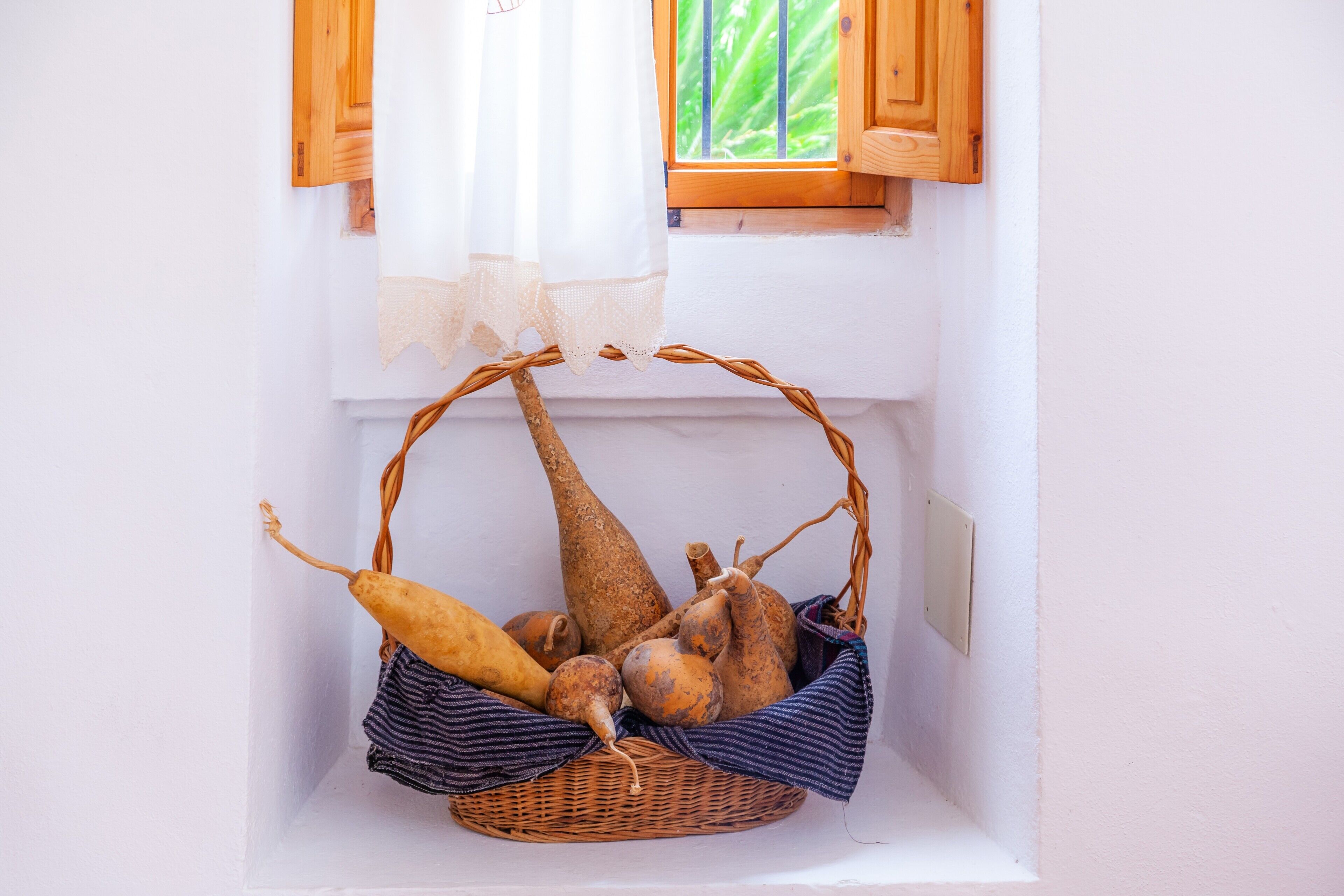 A wicker basket with vegetables in a white window sill.