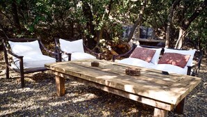 A rustic outdoor seating area with a wooden table and two cushioned chairs. - Cabin between Forest and River  (Lo Barnechea)