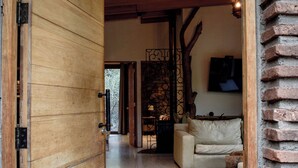 A wooden door leading to a living area with a sofa and a fireplace. - Cabin between Forest and River  (Lo Barnechea)