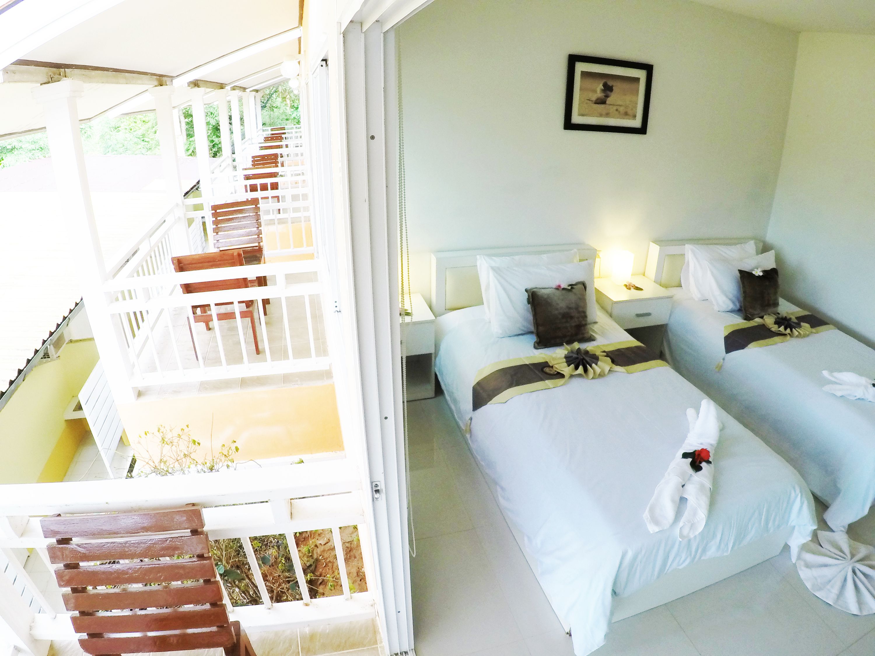 A hotel room with two beds, a staircase, and a framed picture on the wall.