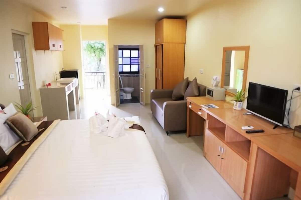 A hotel room with a bed, a desk, a television, and a balcony.