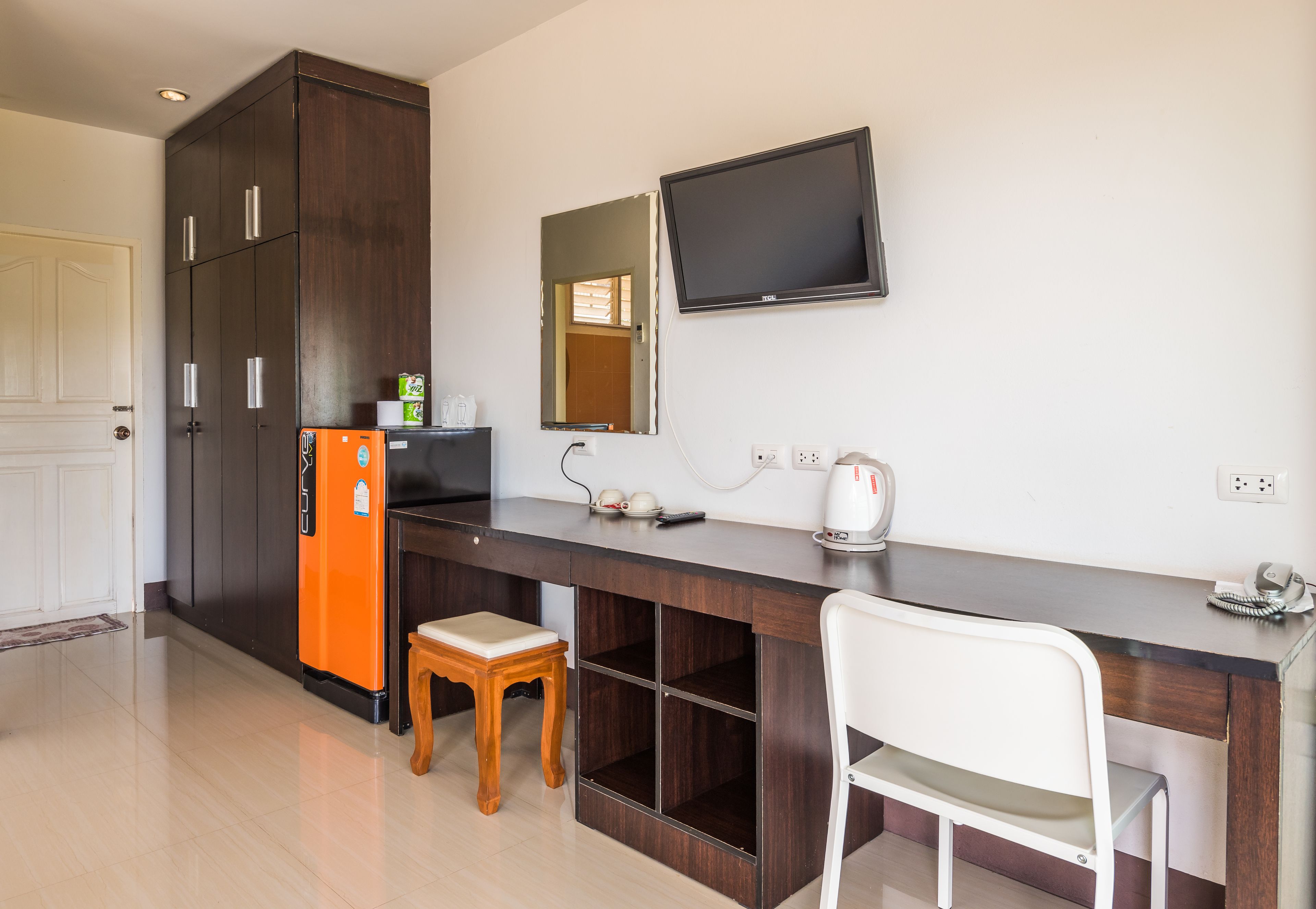 A compact kitchen with a refrigerator, a sink, a countertop, and a chair.