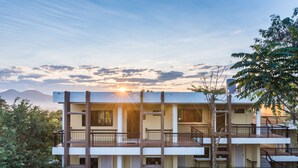 Un edificio de varios pisos con balcones y vista al atardecer.