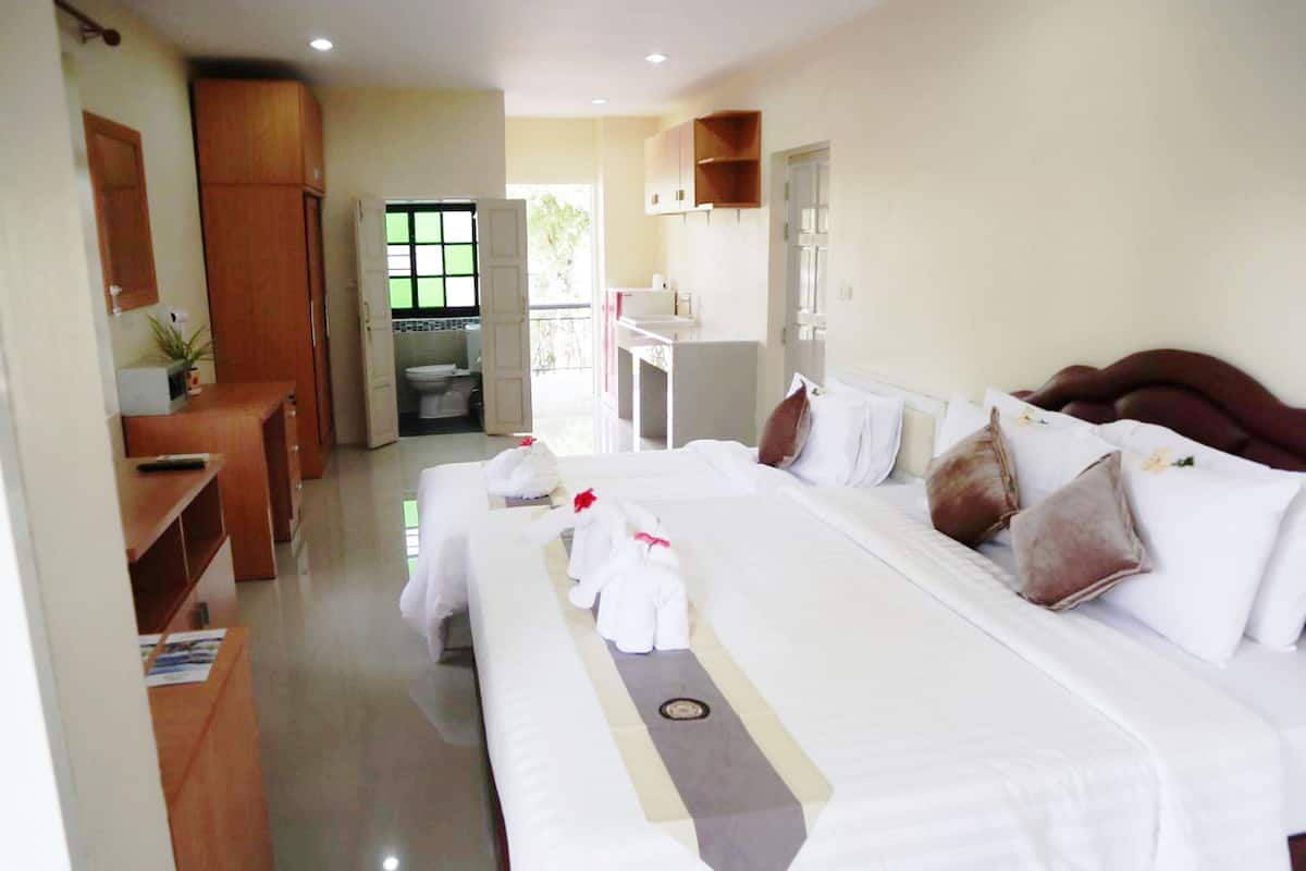 A hotel room with a large bed, a desk, a bathroom, and a view of the outside.
