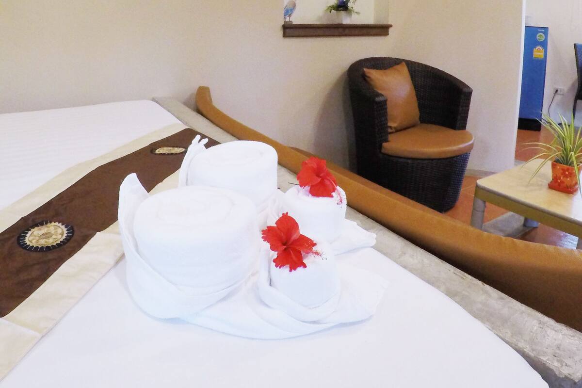 A hotel room with a bed, a chair, and a small table with a plant.