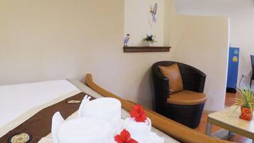 A hotel room with a bed, a chair, and a small table with a plant.