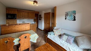 Ett kompakt bostadsutrymme med ett litet kök, en matplats och en soffa.