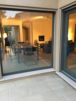 Un intérieur moderne avec une porte vitrée donnant sur un espace repas comprenant une table et des chaises.