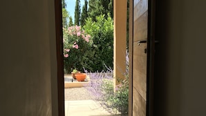Ein offenes Durchgang zu einem Garten mit Kübelpflanzen und Fliesenboden.