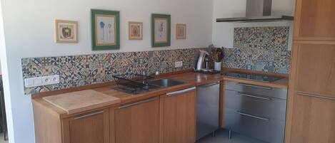 A compact kitchen with wooden cabinets, a tiled backsplash, and a stainless steel sink.