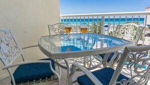 A glass-top table with two chairs, a white railing, and a view of the ocean. - Read my reviews.  Know what you are getting. (Fort Walton Beach)