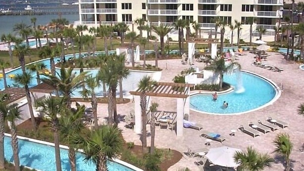 A resort pool area with multiple pools, palm trees, and lounge chairs. - Read my reviews.  Know what you are getting. (Fort Walton Beach)