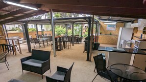 An outdoor patio area with tables and chairs, a covered seating area, and a kitchen area with appliances. - KI Caravan Park, Kingscote (Brownlow Ki)