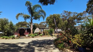 A garden with a gravel path, various plants, and a structure with a curved roof. - KI Caravan Park, Kingscote (Brownlow Ki)