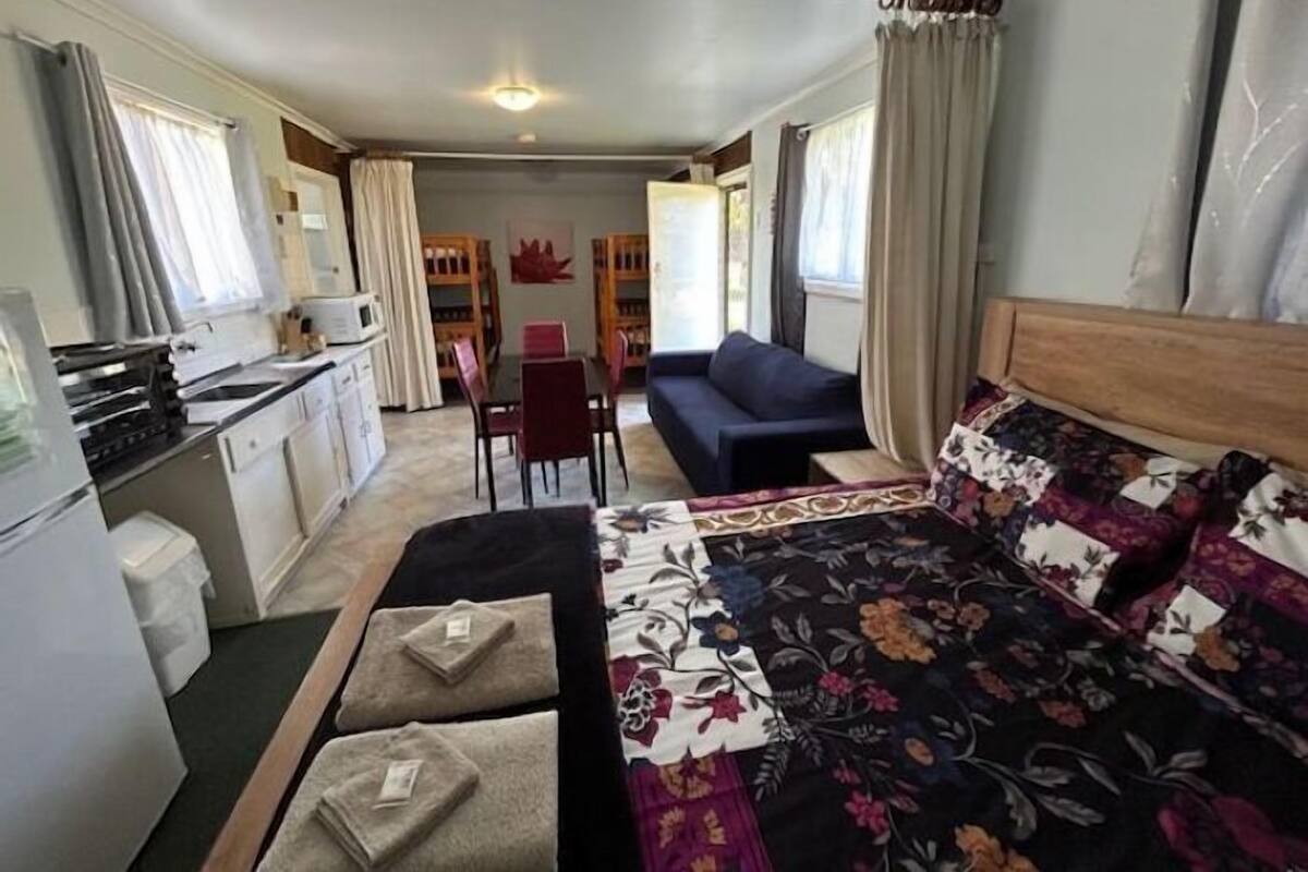 Een compacte kamer met een bed, een kleine kitchenette, een zithoek en een slaapbank.
